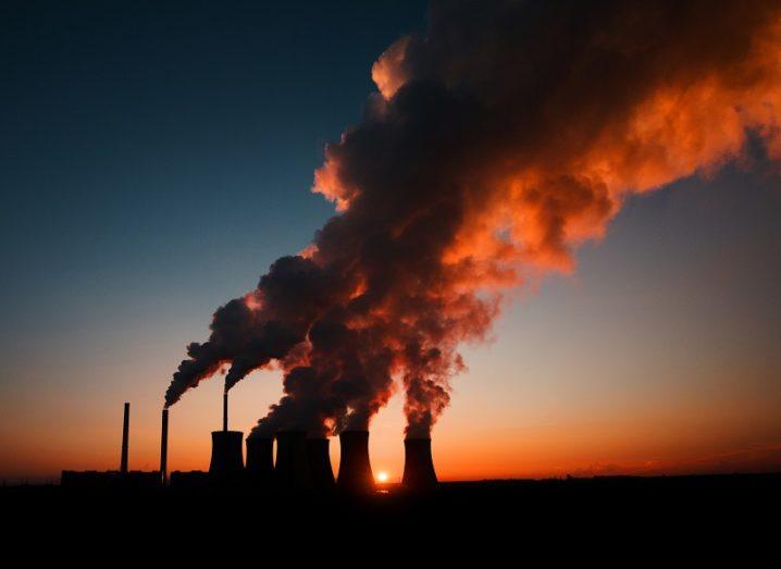 Distant shot at dusk of large power station emitting CO2.