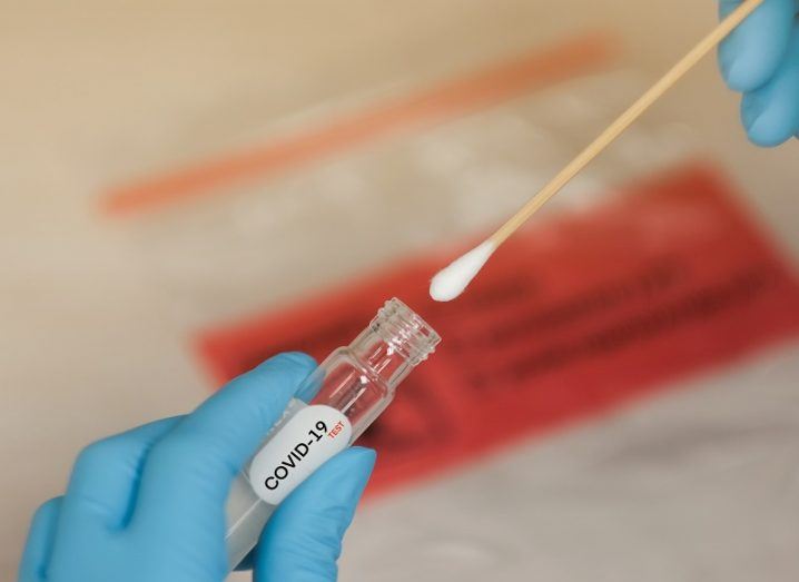 Covid-19 test swab being placed into a test tube.