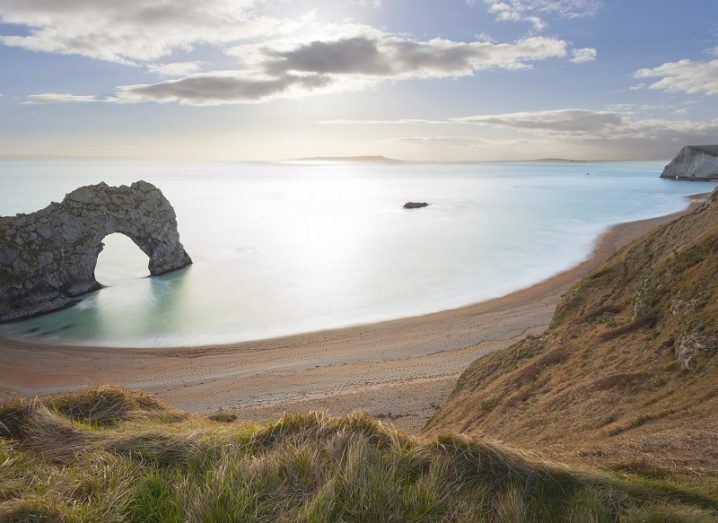 Sunny day at Durdle Door, Dorset with a rock formation jutting out into the sea.