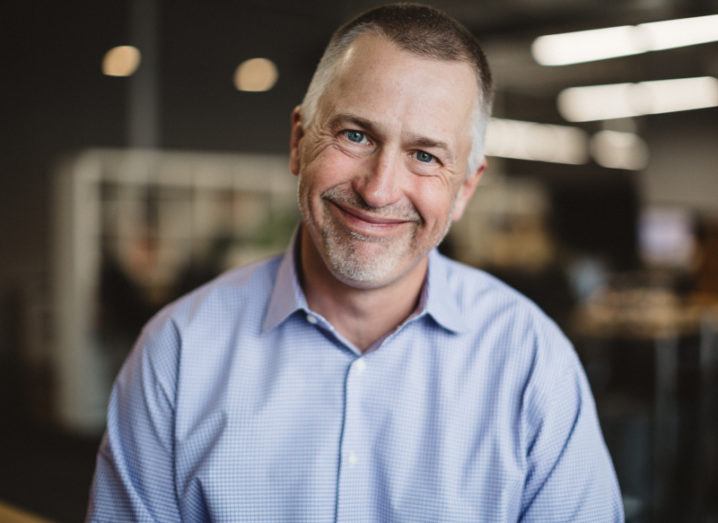 Joe Tobolski of Nerdery is smiling into the camera in a modern corporate space.