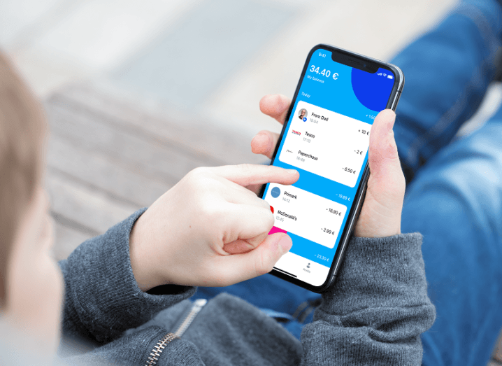 Child's hand using the Revolut Junior app on a smartphone.