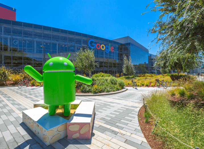 The Google offices in California under a clear blue sky, with grass, trees, shrubs and an Android statue outside.
