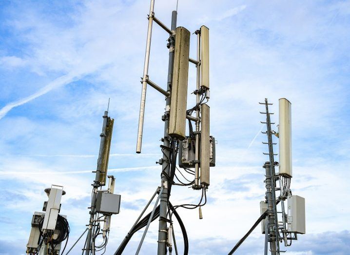 Four 5G base stations against a thinly-clouded blue sky.