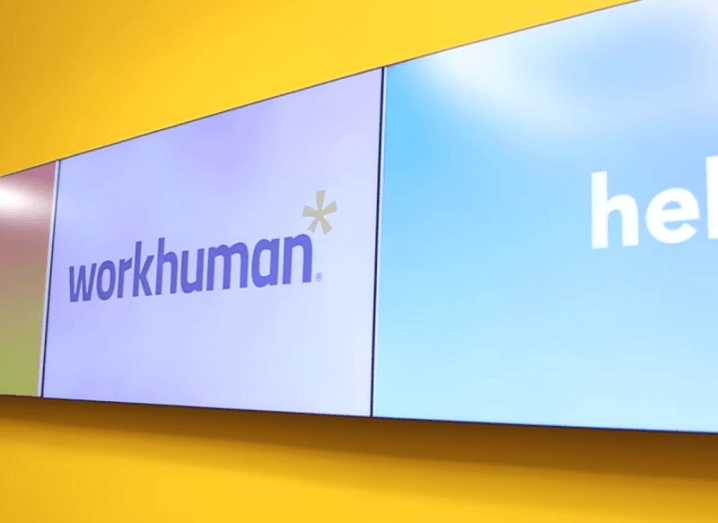 The Workhuman logo on a TV screen against a yellow wall.