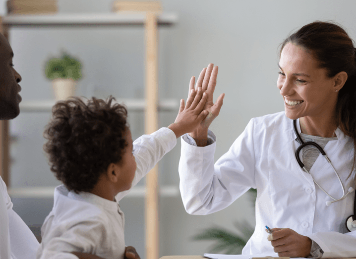 A doctor giving a high-five to a young patient.