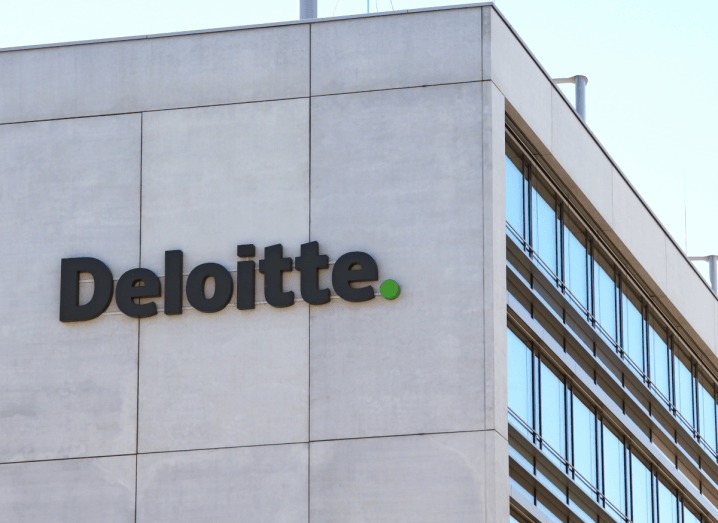 The Deloitte logo on the side of a concrete office building.