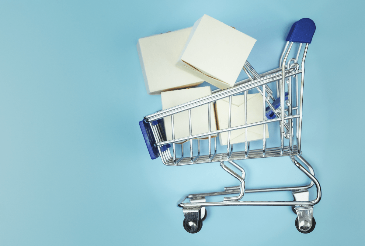 A shopping cart with white boxes in it in front of a blue background.