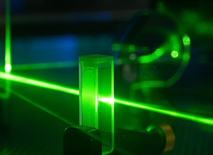 Green laser shining through a glass block in a quantum research lab.
