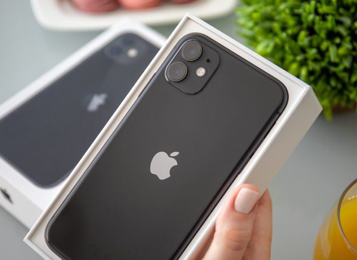 Hand holding an iPhone 11 box with a black phone inside.