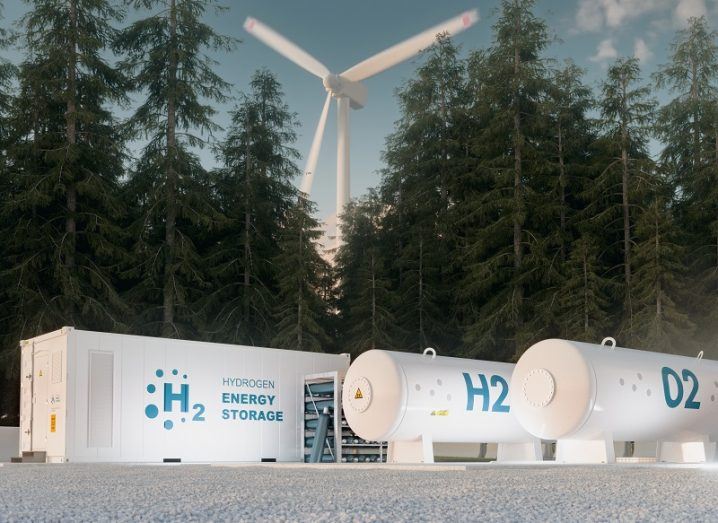 Concept of a hydrogen fuel production station beside a forest and a wind turbine.