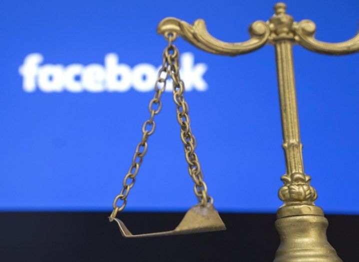 Legal scales in front of a screen with the Facebook logo on it.