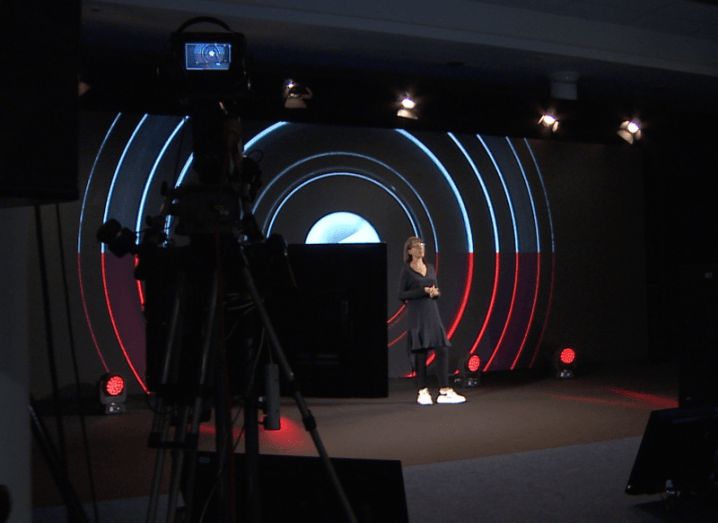 Ann O’Dea stands in front of a huge LED screen displaying Future Human graphics. In the foreground we can see large TV cameras filming her presentation.