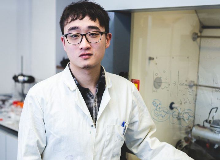 Dr Yikai Xu in a white lab coat and glasses in a lab.