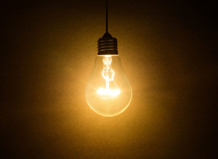 A switched-on light bulb against a black background, representing digital transformation.