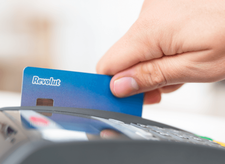 A hand swiping a Revolut card on a card reader.