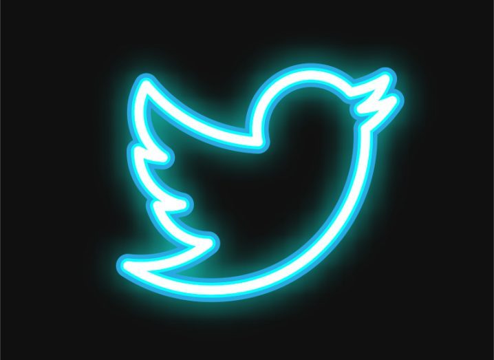 A neon outline of the Twitter bird logo against a black background.