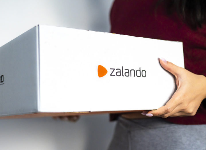 A person holding a white delivery box with the Zalando logo on the side.