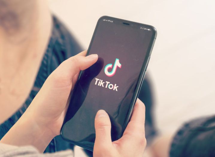 A woman is using the TikTok app on her mobile phone.