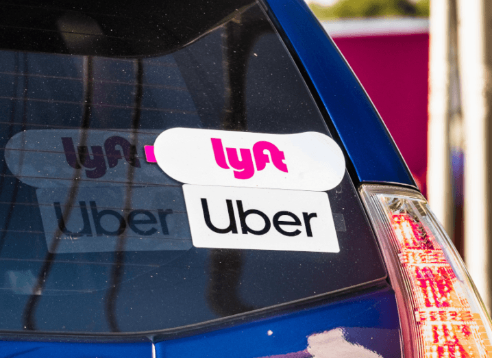 Uber and Lyft stickers on the back of a car.