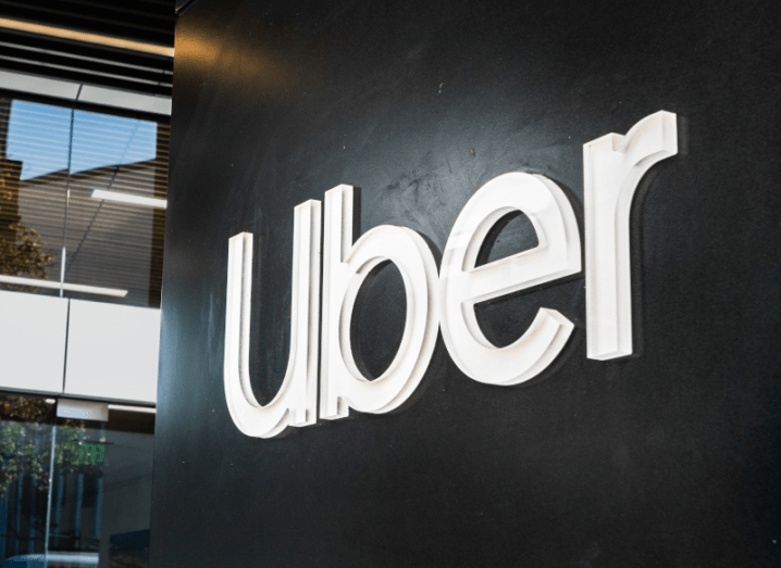 The Uber logo against a black wall.