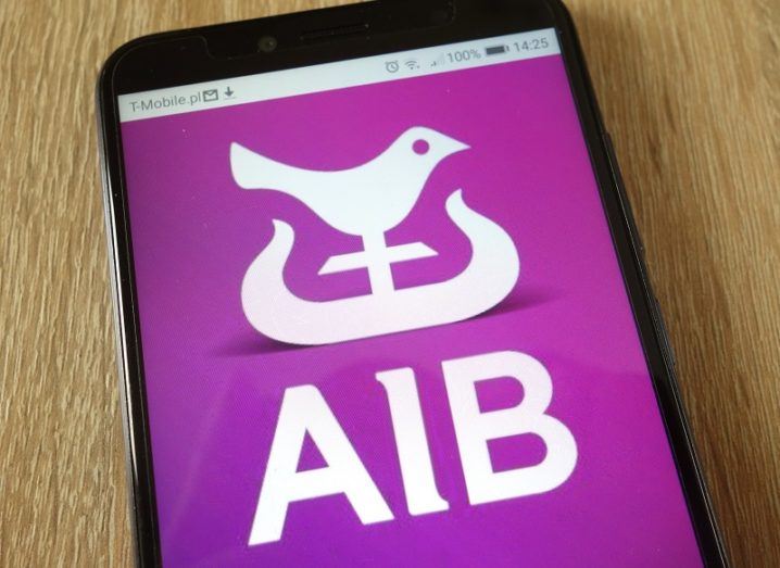 The AIB logo on a phone placed on a wooden table.