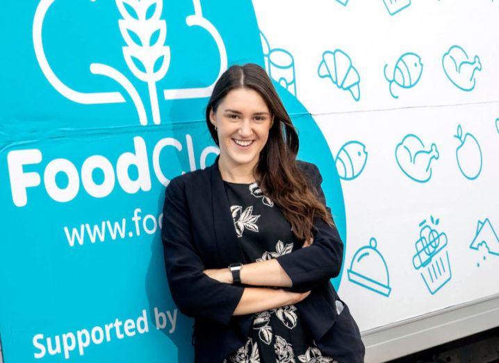 Iseult Ward leans against a white and blue van with the FoodCloud logo on it.