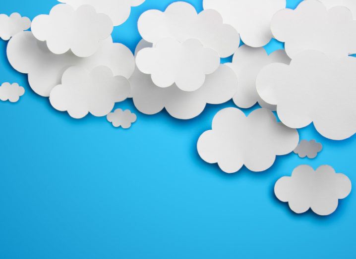 Clouds cut out of paper against a blue background, representing digital transformation and cloud computing.