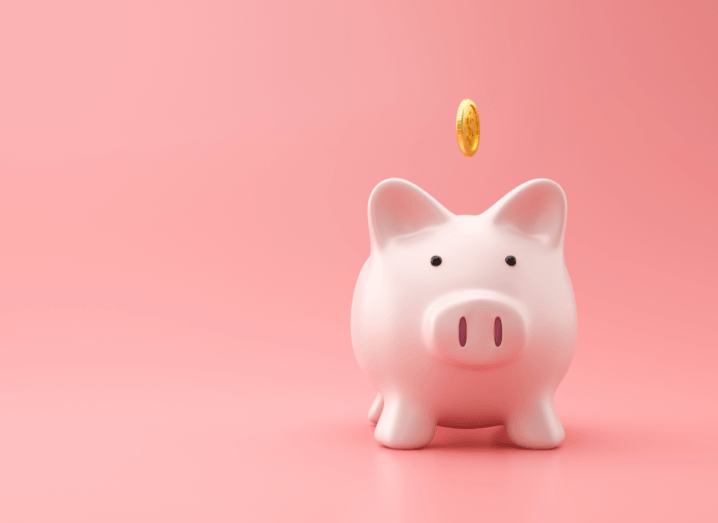 A piggy bank in front of a pink background.