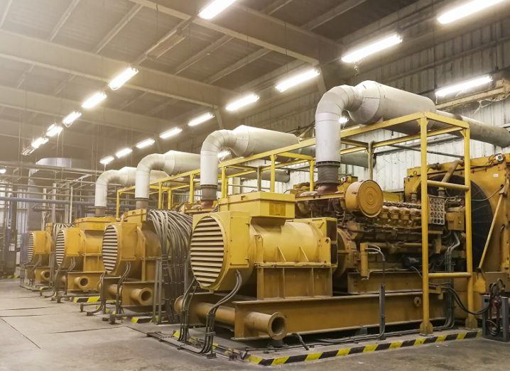 Yellow large diesel electric generators in a brightly lit room.