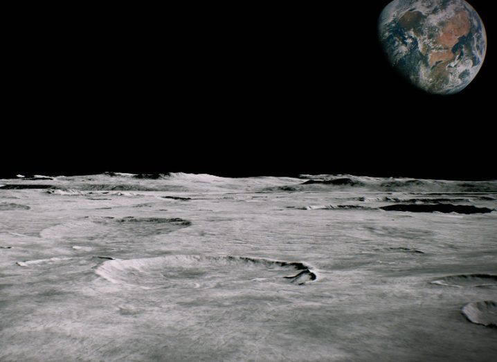 Surface of the moon landscape with Earth visible in the background.