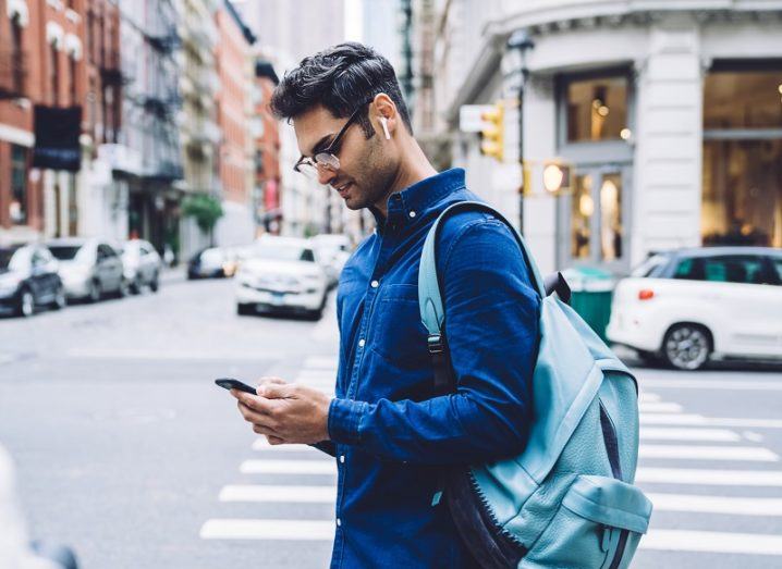 Man in a blue shirt looking at his phone on a New York street.