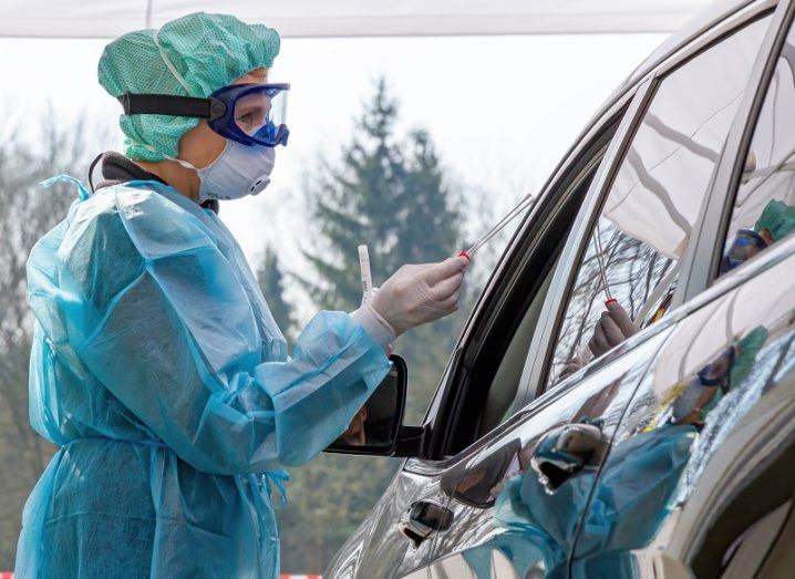 Person in full PPE at a coronavirus drive-through testing station.