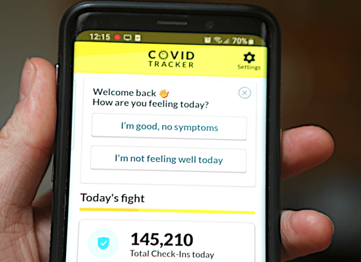 Hand holding a phone with the Covid Tracker app open.