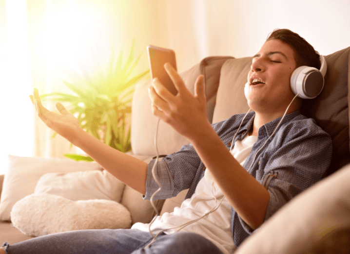 A person singing into his phone on a sofa.