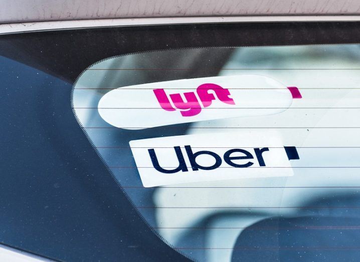 A rear window of a car with Uber and Lyft stickers attached.