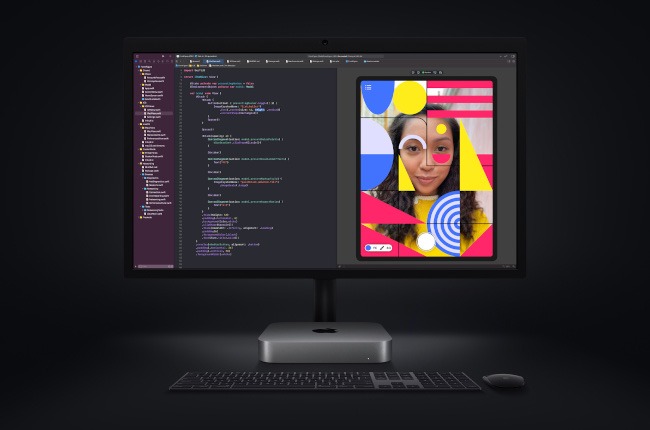 A desktop computer set-up with the Mac Mini. The screen shows coding on the left-hand side with an image of a girl on the right stylised with graphics.