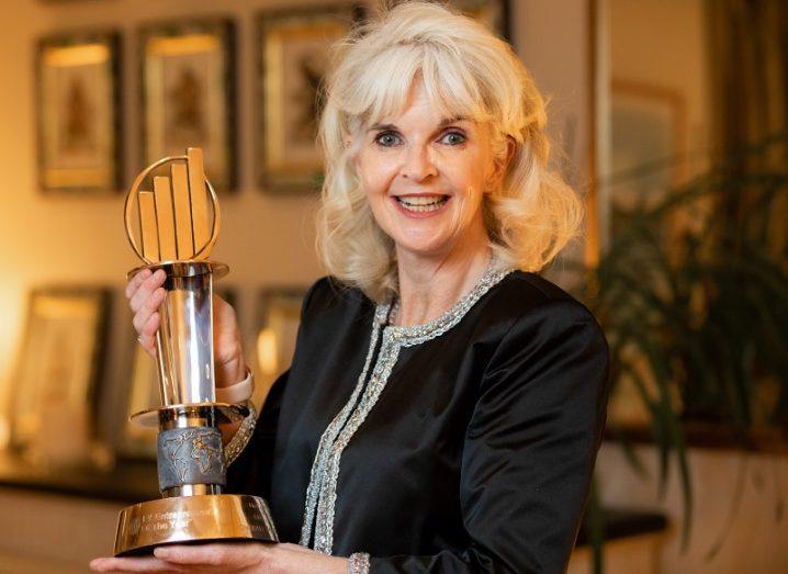 Nicola Mitchell in a black top smiling and holding her EY Entrepreneur Of The Year award.