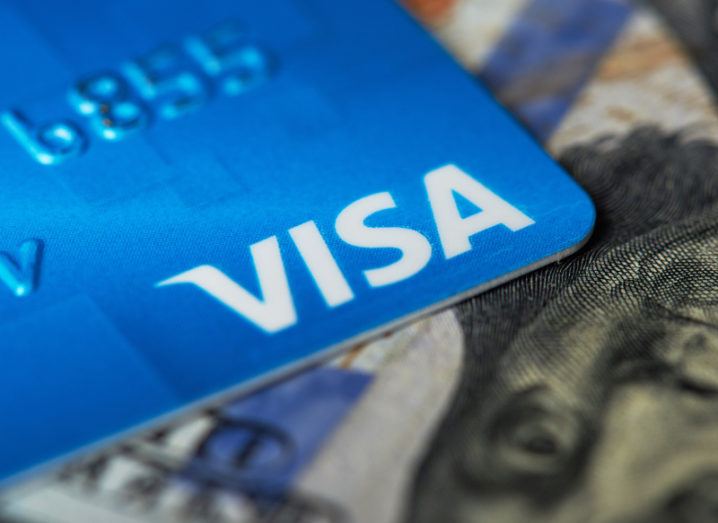 A blue visa card is sitting on a US dollar bill.