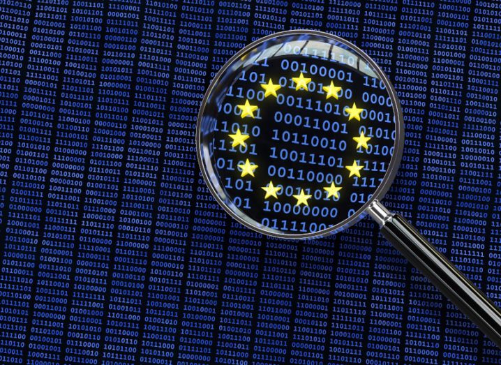 A magnifying glass examining binary code zooms in on a European Union symbol of a circle of yellow stars.