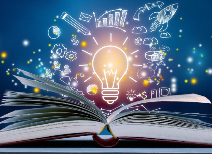 A book is lying open on a table, under an illustration of a lightbulb and other images relating to business and innovation.