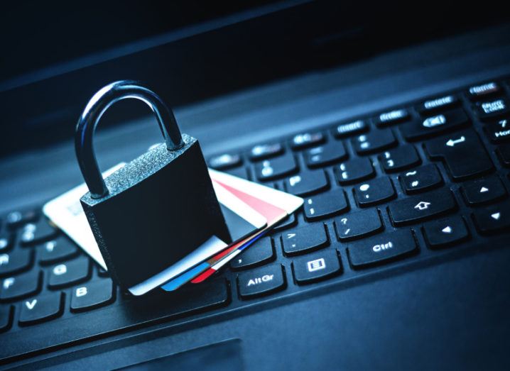 A padlock and a number of credit cards sit on top of a laptop keyboard.