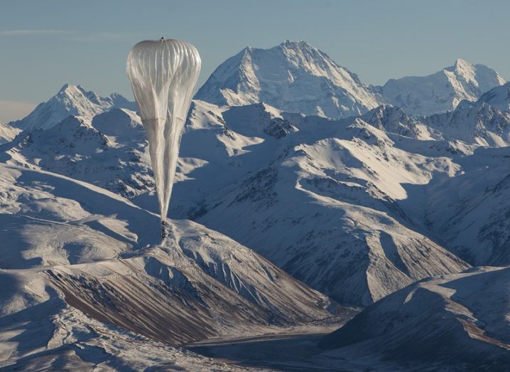 Google's internet balloons flying in the sky over mountain terrain.