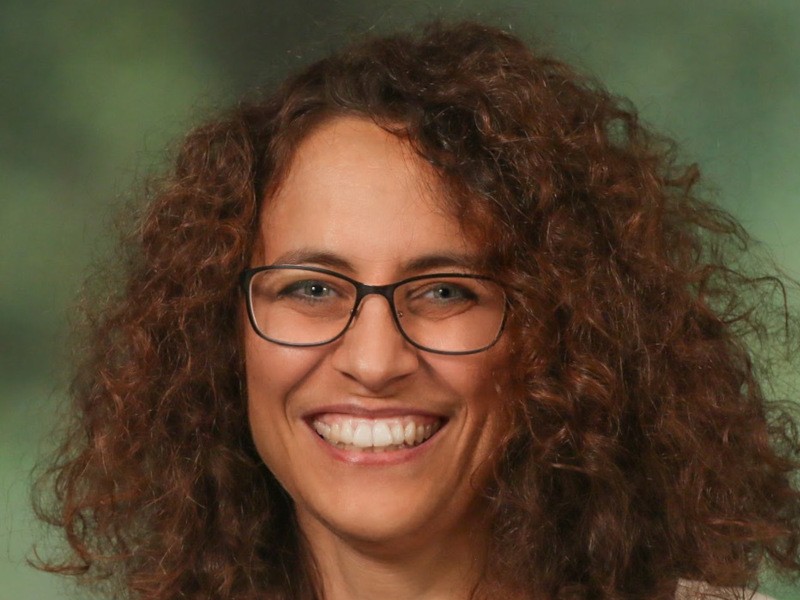 Rosaria Silipo, data science evangelist at Knime, is smiling into the camera while wearing glasses against a green background.