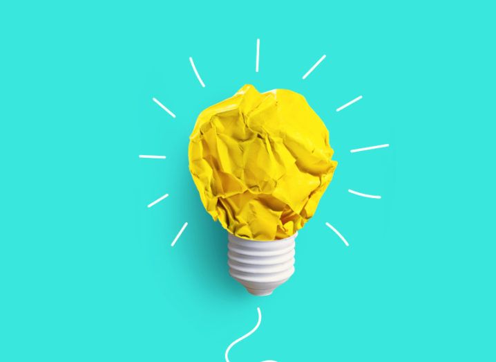 A bright blue background with a lightbulb on it. The bulb itself is made of a scrunched-up piece of yellow paper.