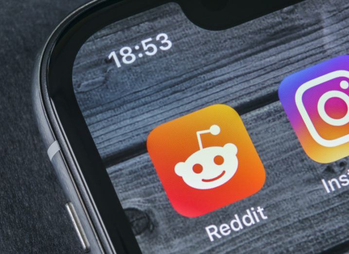 A close-up of the top left-hand corner of a smart phone showing the Reddit app logo on the screen.