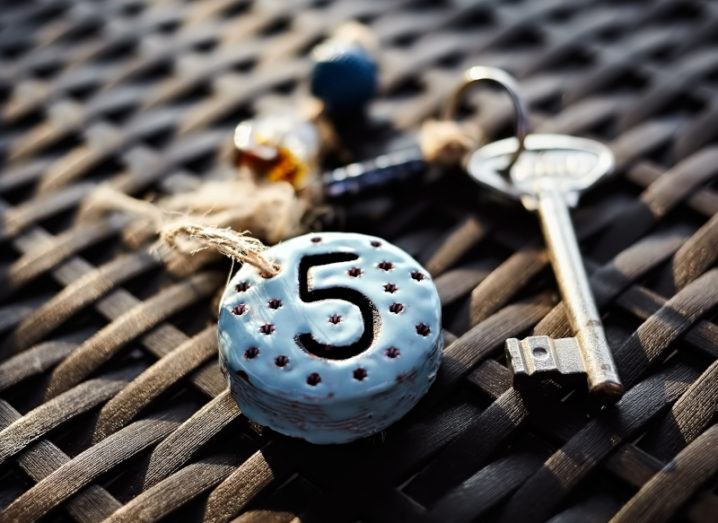 A key with a keyring that says the number five on it lies on a wicker mat.