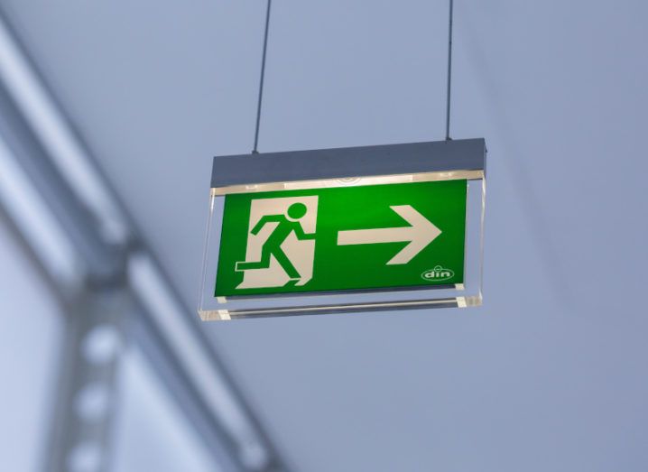 A green emergency exit sign is lit up in an office building.