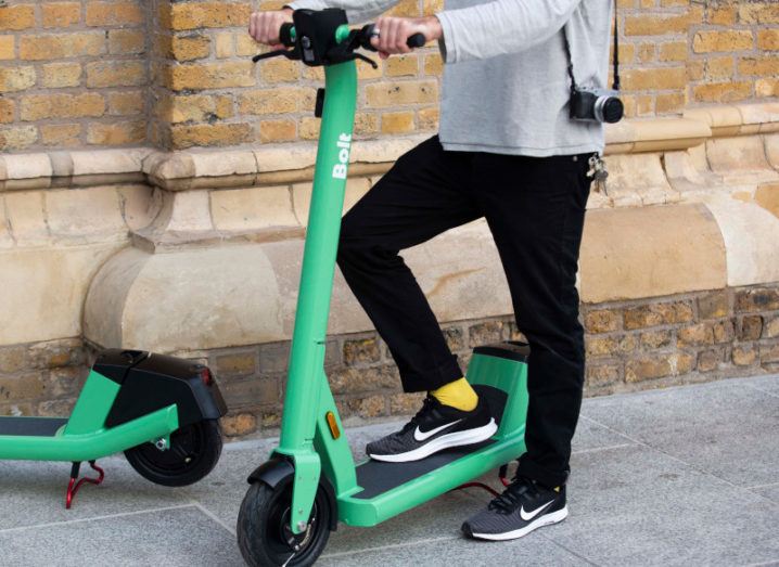 Photo of a person using one of Bolt's bright green e-scooters.