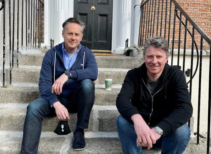 Two men sit in casual clothes on the steps of a Georgian building in Dublin. They are Strike founders Oli Cavanagh and Charles Dowd.