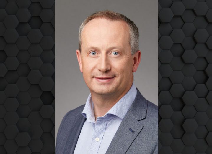 Headshot of a man in a grey-blue blazer and pale blue shirt.